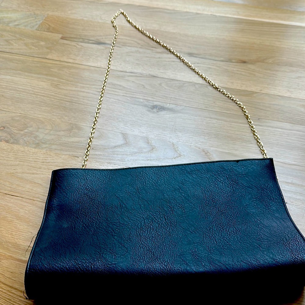 Oversized black clutch with gold chain and tassels